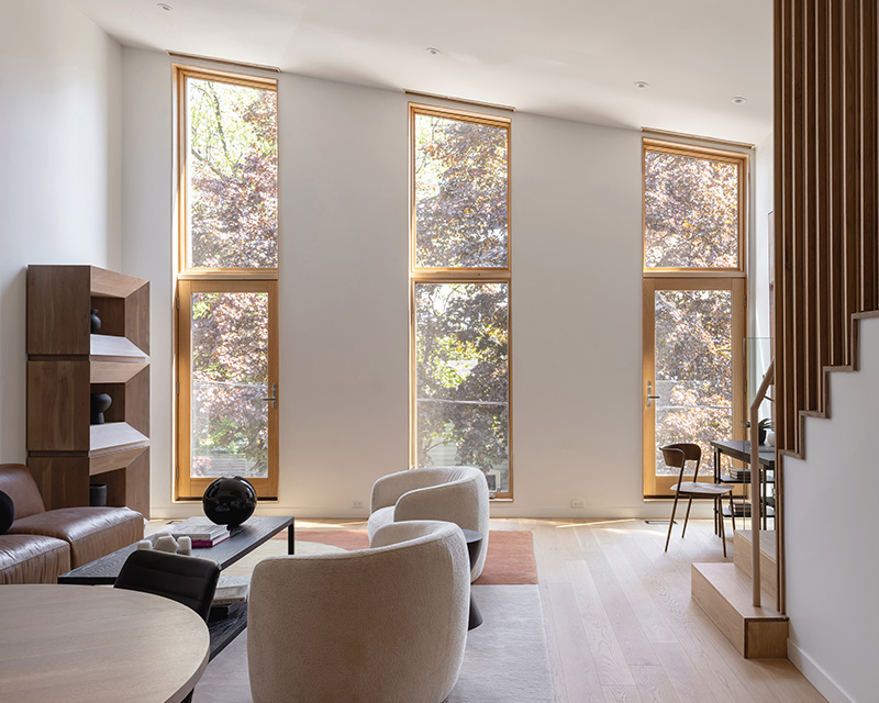 A bright room with a set of chairs and couch with a staircase on the right side