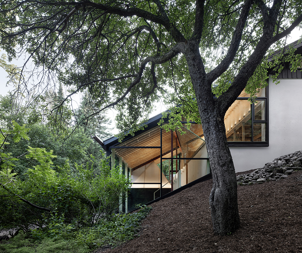 A white and black house with large windows on a hillside