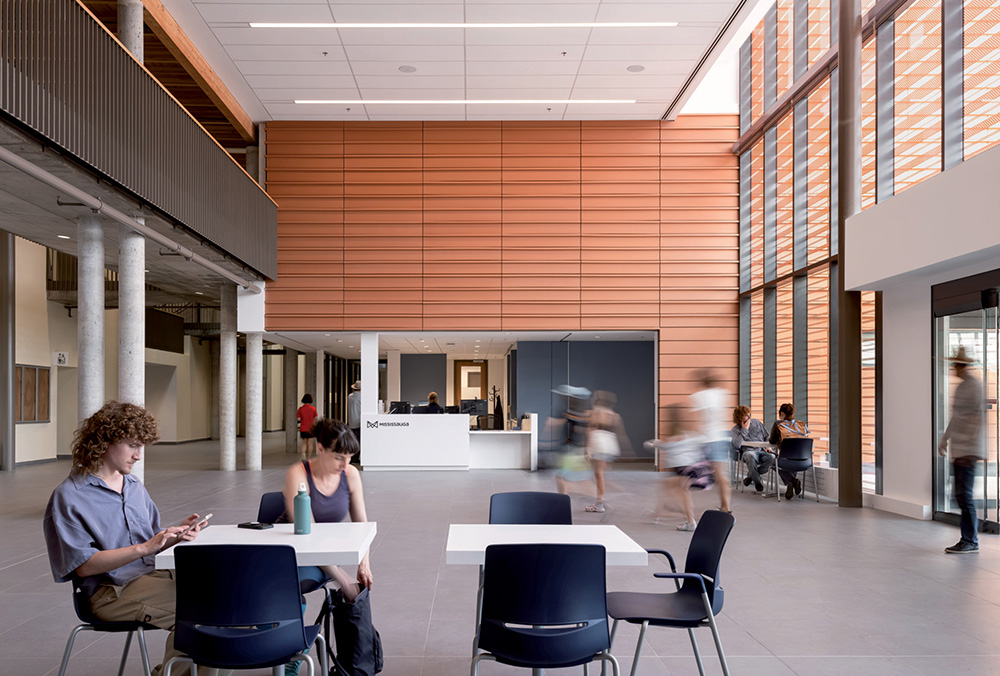A spacious lobby with concrete columns and people sitting near a central reception desk