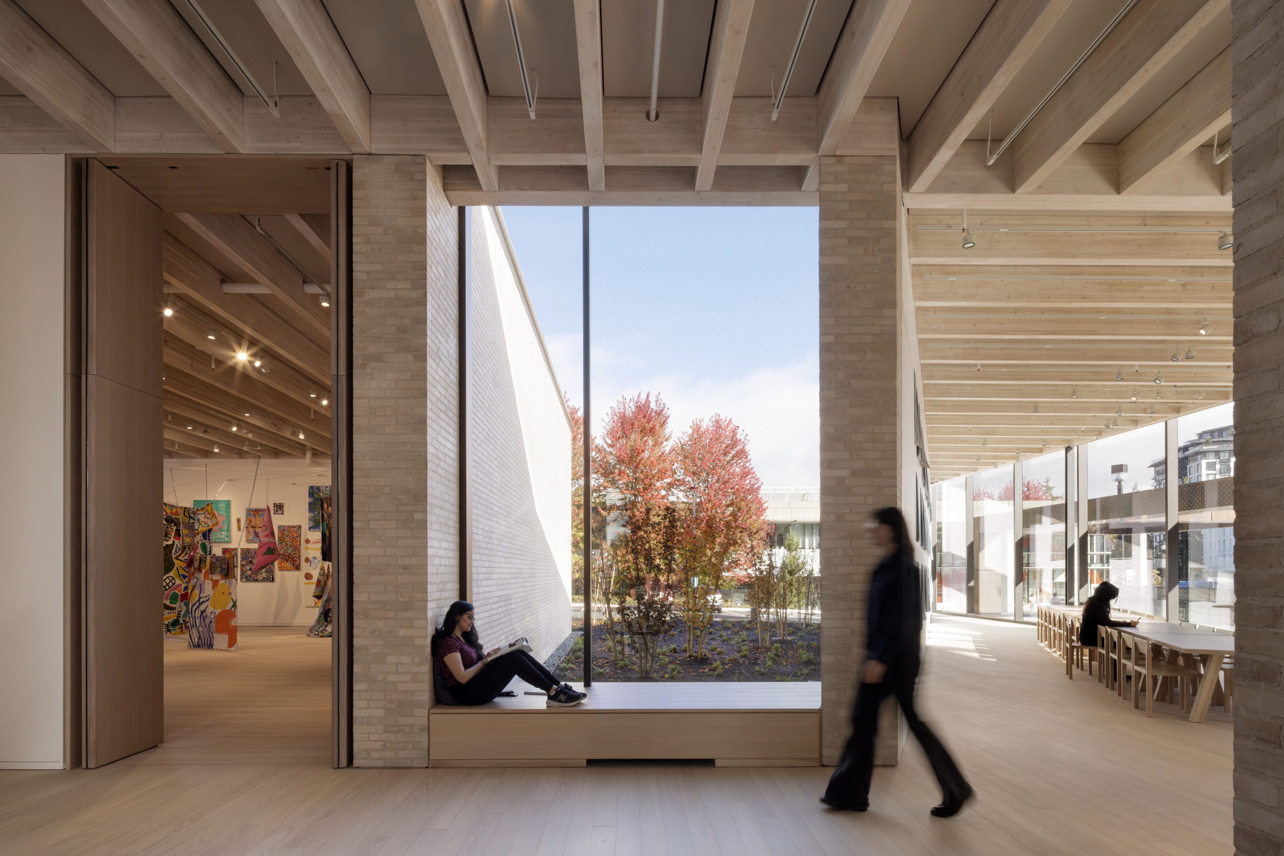 A large window in a sharply angled room with exposed roof structure and tan bricks