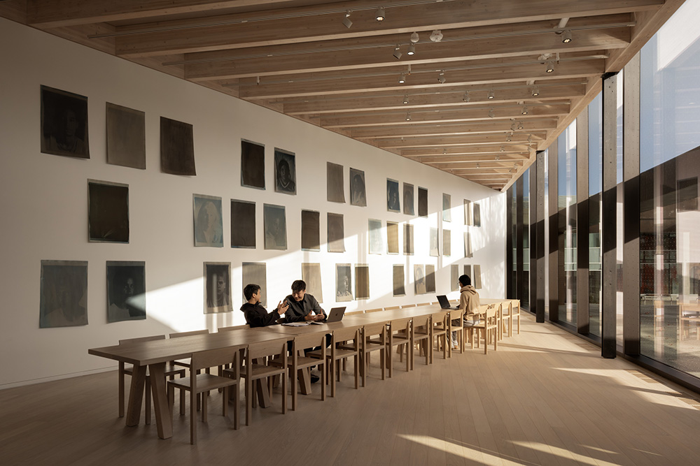 A bright, minimalist room with a long wooden table beneath tall windows
