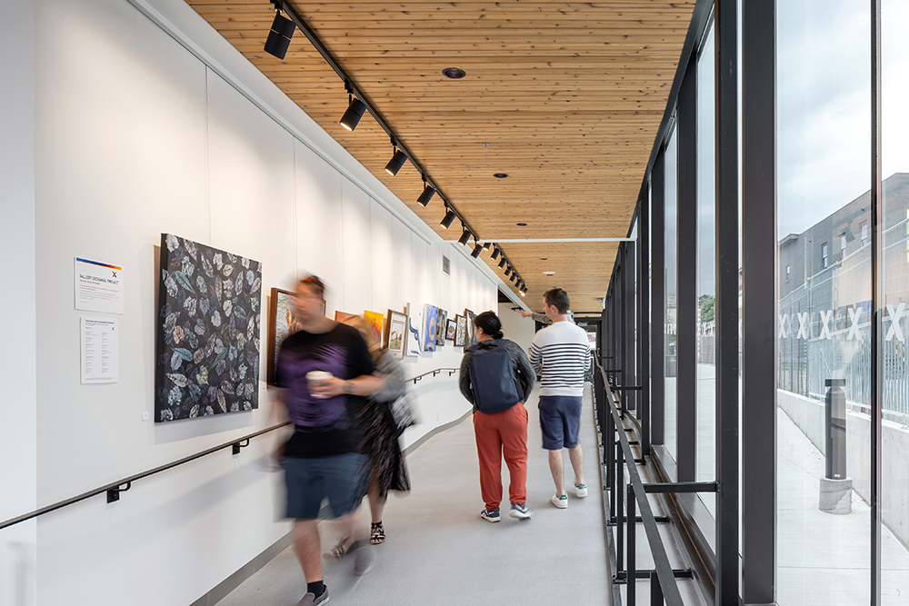 A hallway with a curtainwall on one side and a white wall with artwork hanging on the other