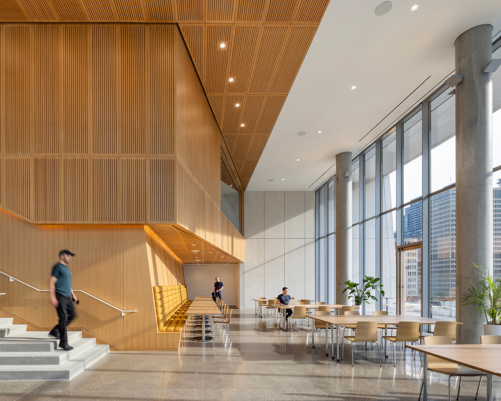 A bright common area with tall windows wood paneling and concrete columns