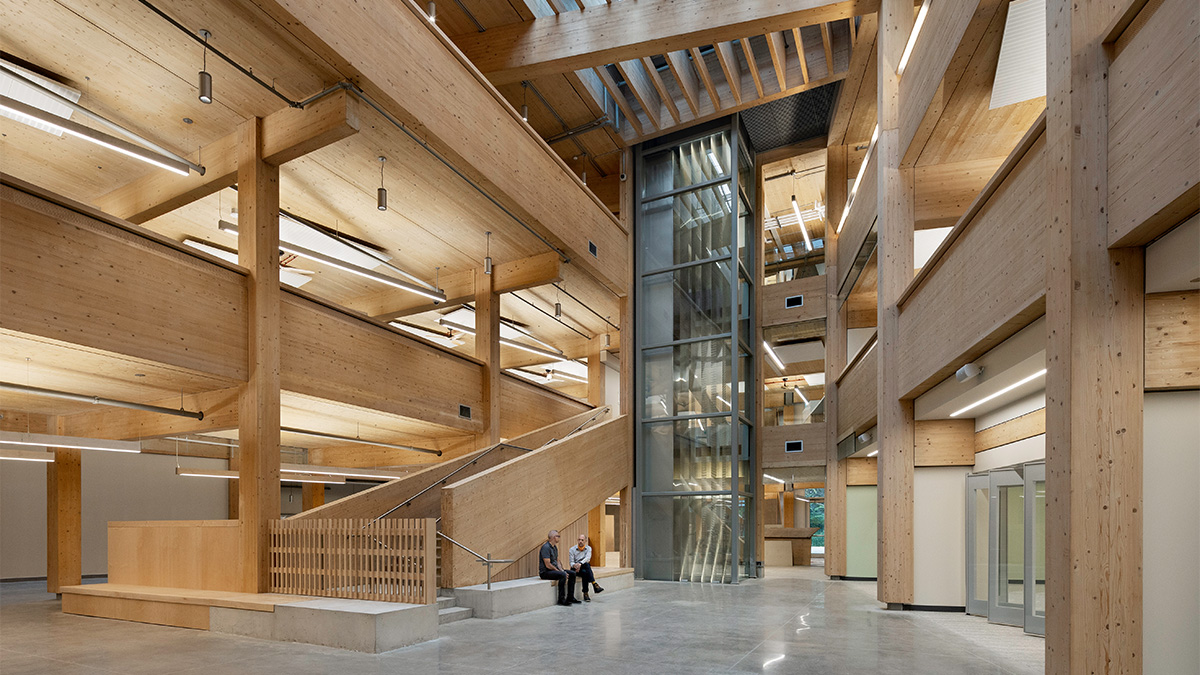 A bright, modern interior with tall glass windows, polished concrete floors, and wooden slatted walls and ceilings