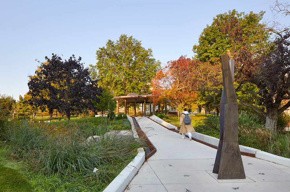 A tree‑lined path beside a tall metal pavilion in a park