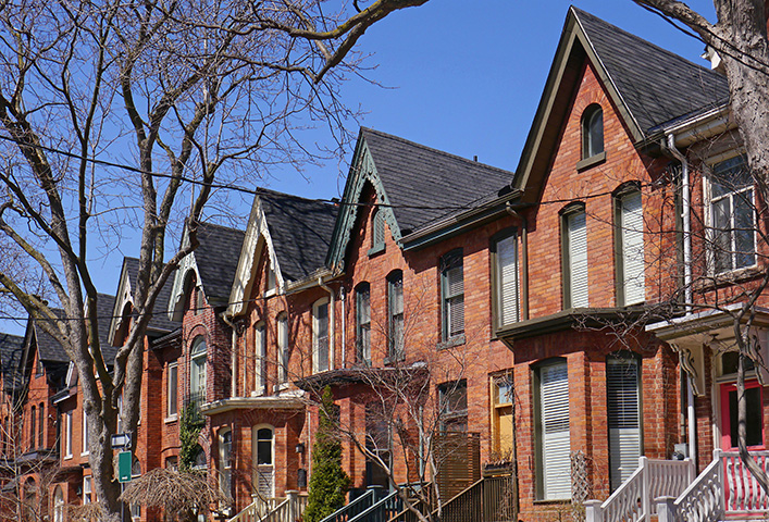 Row of semi-detached Bay-and-Gable red-brick houses with trees in the foreground