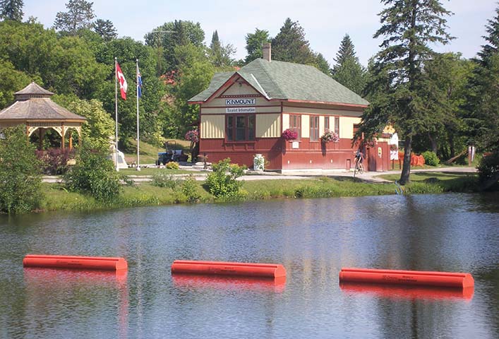 Small railway station with brightly-coloured exterior in a forested area alongside a river. 