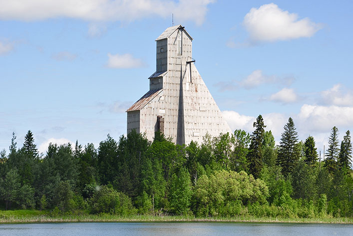 Wood-clad mine headframe with lake and forest in foreground