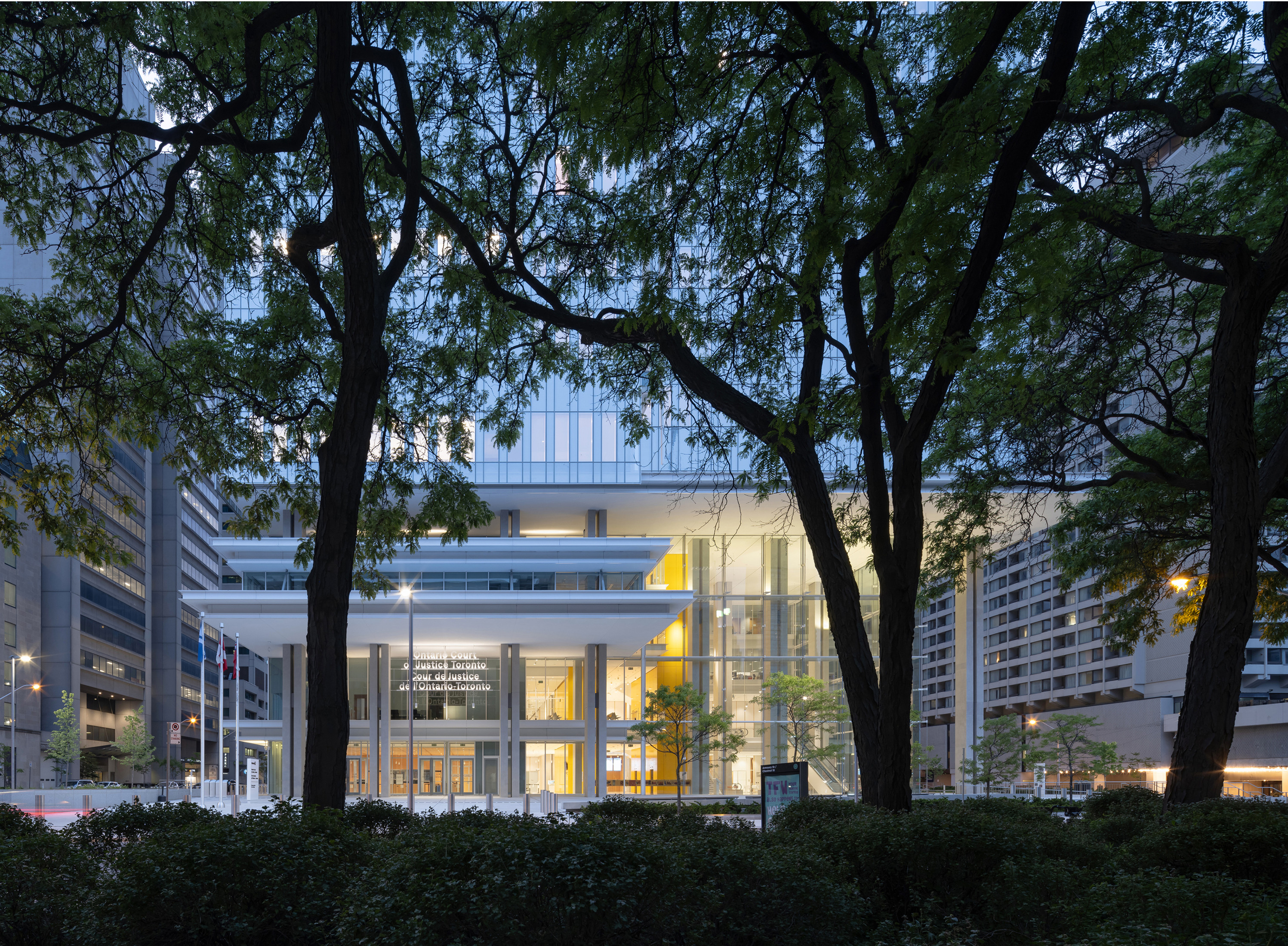 Exterior view looking north from the Superior Court of Justice with the main entry to the left, atrium to                           the right, yellow elevator core visible on interior between entry and atrium.