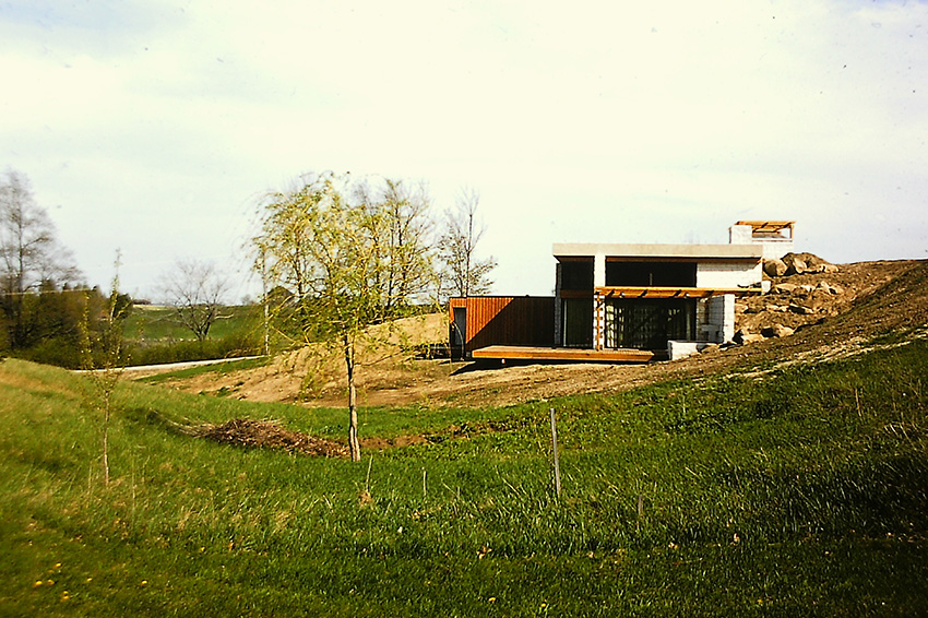 A low house with a deep roof overhang in a field