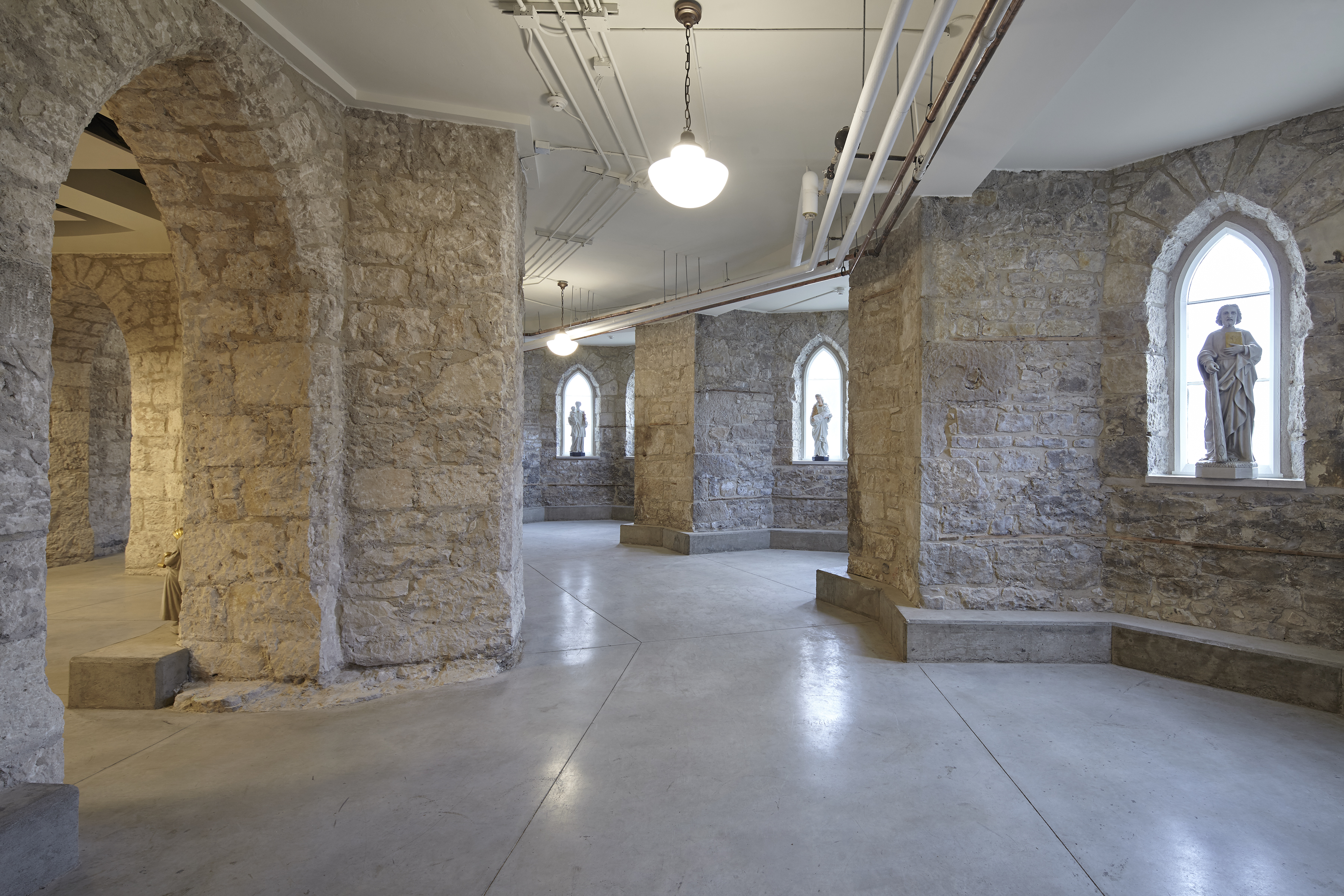 Restored interiors of the basilica, showcasing stone walls, archways, and modern lighting elements.