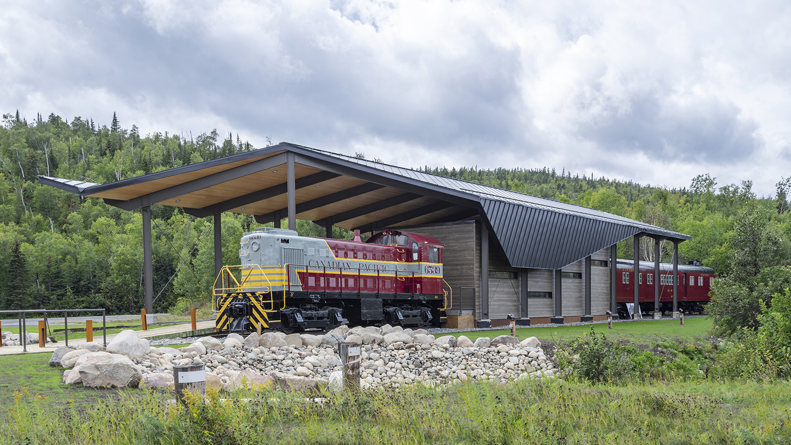 Main view of the Schreiber Discovery Centre, showcasing its modern shelter with a timber and steel structure, set against a forested backdrop.