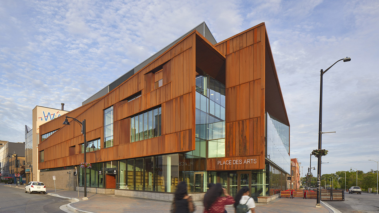 Perspective of a building with angular oxidized steel facade and curtain wall windows.