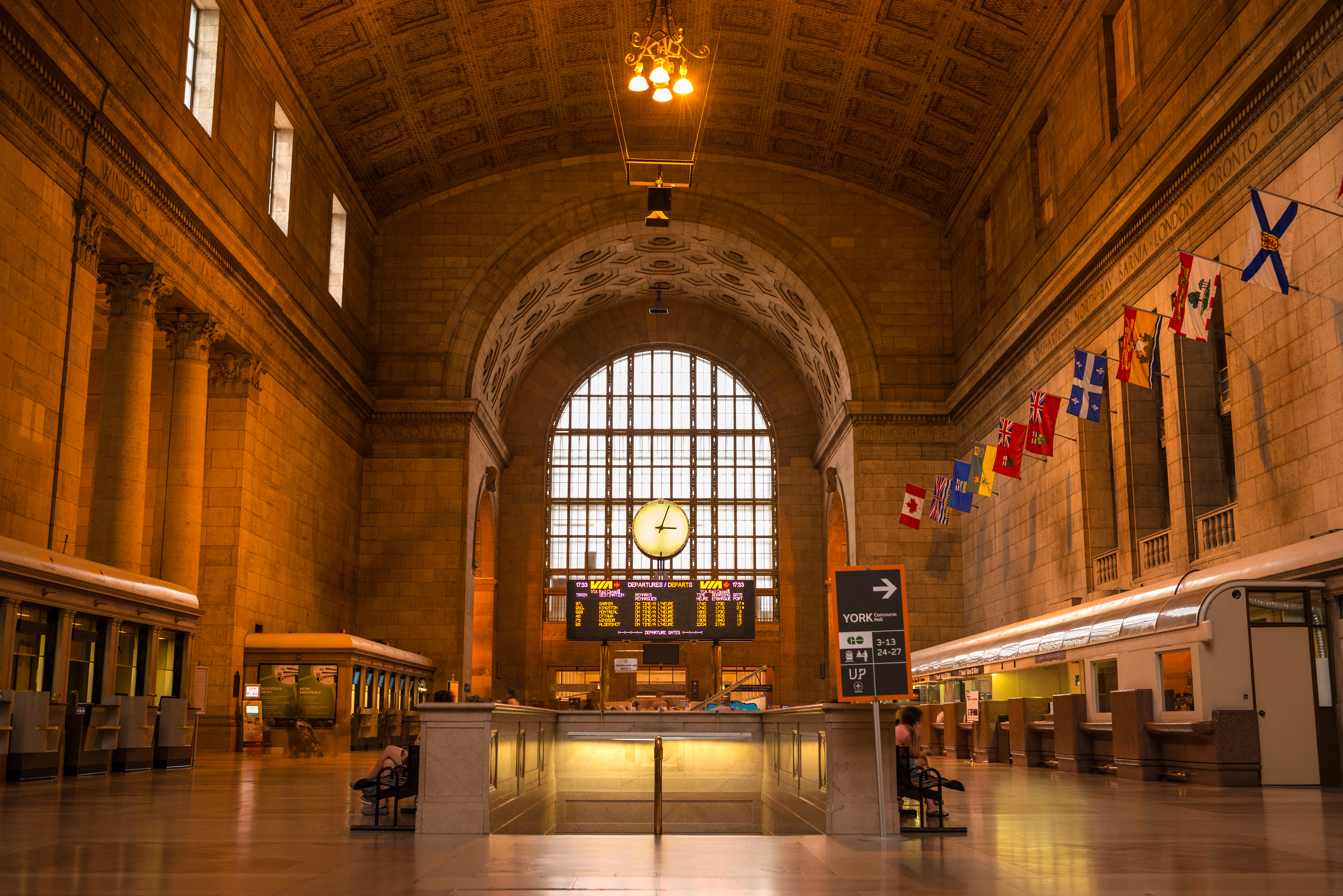 A large interior space with a tall arched ceiling and a large clock in the middle.